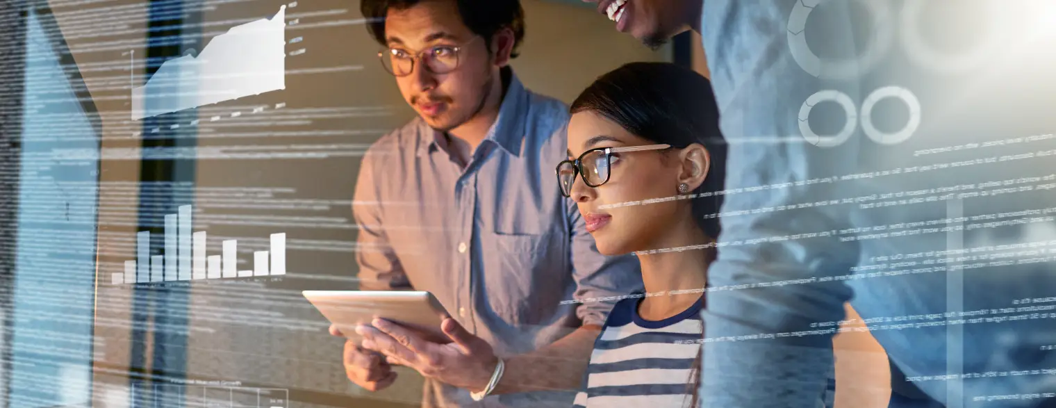 Three professionals collaborating in an office while reviewing digital data and charts displayed on a screen
