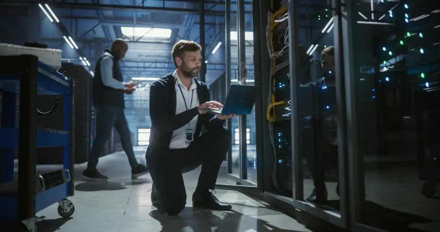 Two technicians working inside a brightly lit data center with rows of server racks