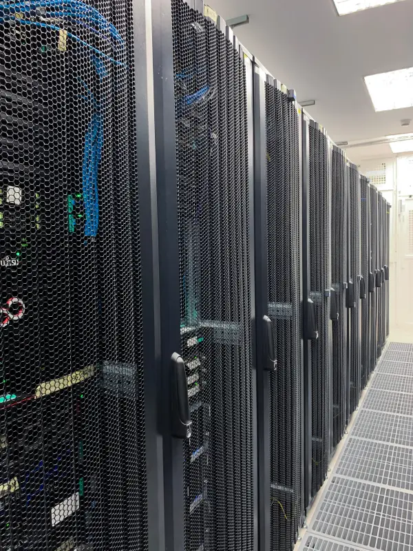A row of black server racks inside a data center with visible cables and equipment