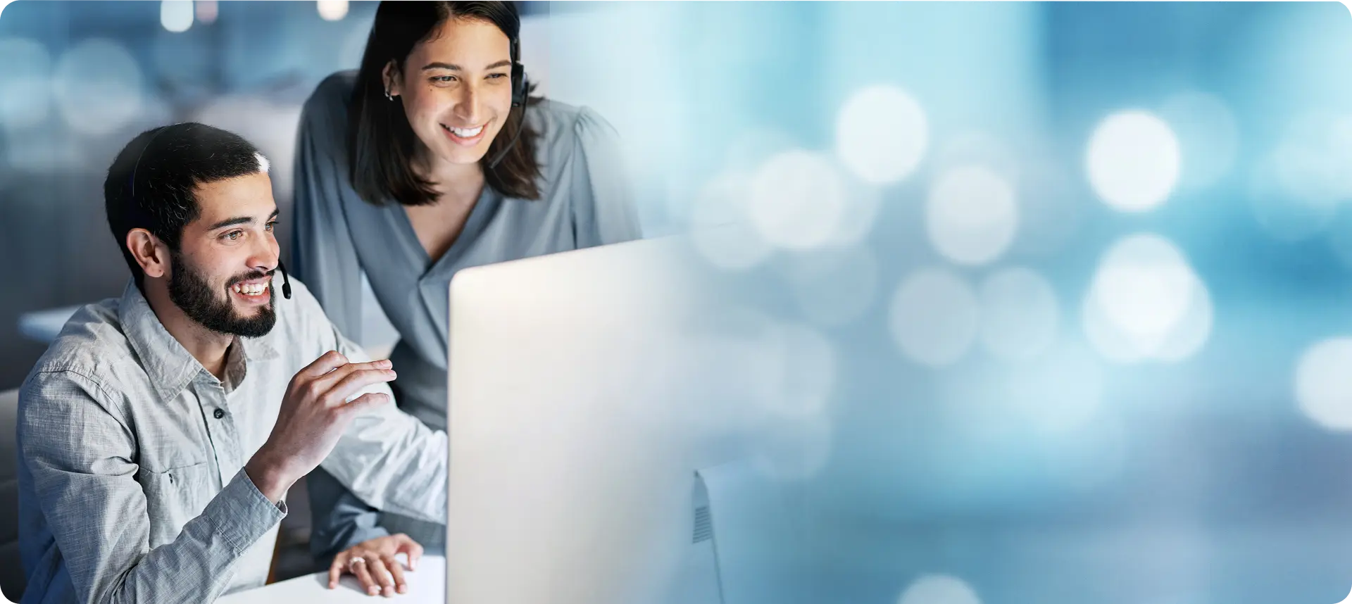 Two IT consultants collaborating in an office while looking at a desktop computer