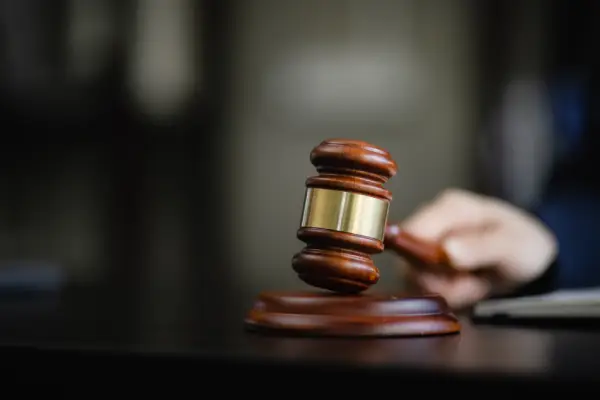 Close-up of a wooden gavel resting on a sounding block in a courtroom setting