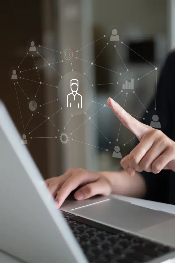 Person using a laptop with a digital network graphic showing connected user icons and data nodes hovering above the keyboard